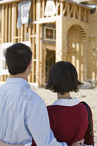 审视未完成的住房结构的成熟夫妇肩并肩站立的近视观图片