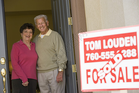 站在新房子门口的一对快乐的老年夫妇的肖像图片