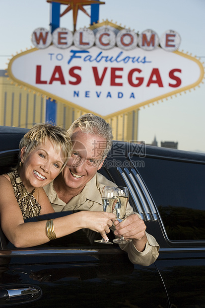 快乐的成熟情侣在豪华轿车里烤白酒 和背景中的拉斯维加斯图片