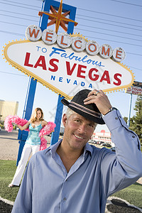 一个快乐成熟男人的肖像 与女人戴帽子和拉斯维加斯标志在背景图片