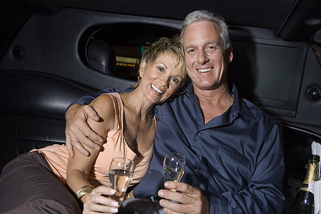 一个快乐的成熟夫妇的肖像 香槟坐在豪华轿车上图片