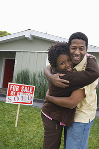 一对非裔美国人夫妇在新房子前拥抱的肖像 他们图片
