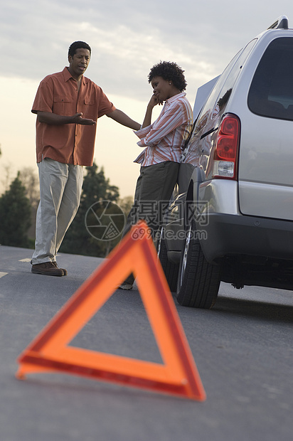 非裔美国夫妇在讨论车撞坏和前方警示三角形的问题时图片