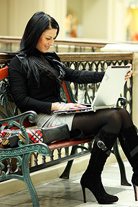 坐在长椅上的美丽的年轻女士女性电脑商业互联网店铺皮革城市学生女孩成人图片