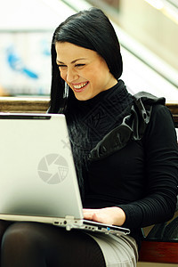 坐在长椅上的美丽的年轻女士商业成人女性教育皮革快乐电脑店铺学生城市图片