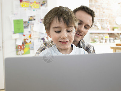 小男孩和爸爸在家一起用笔记本电脑图片