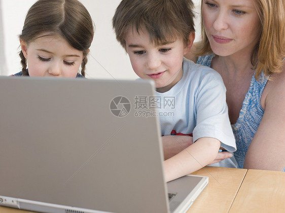 在家桌上使用笔记本电脑的母亲和儿童图片