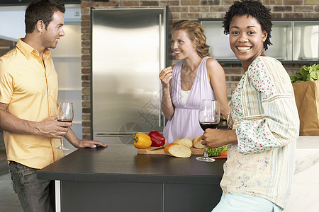 在厨房柜台有朋友的 快乐的年轻非裔美国女人的肖像图片