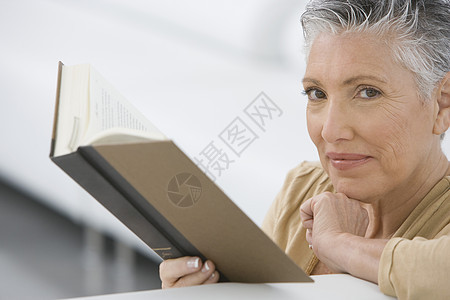 高级女性在沙发上阅读书籍的近视肖像图片