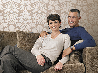坐在沙发上的幸福情侣的肖像微笑房子感情异性丈夫男人婴儿夫妻成人女性图片