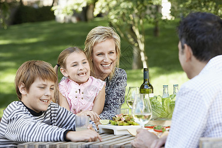 四口幸福的一家四口 享受食物 在公园桌边喝酒图片