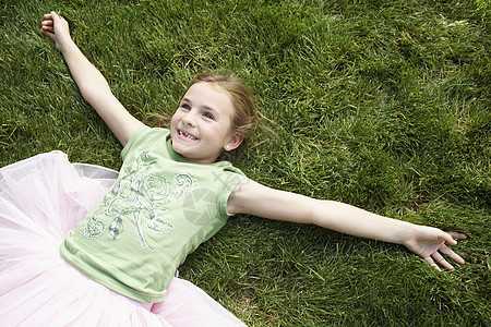 微笑的年轻女孩的高角度视野 双臂伸展躺在草地上图片