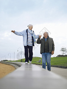 高龄夫妇手握双手在墙上行走图片