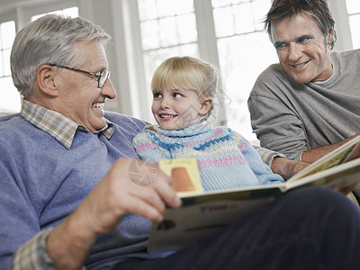 带着父亲和祖父在家中读故事书的年轻女孩图片