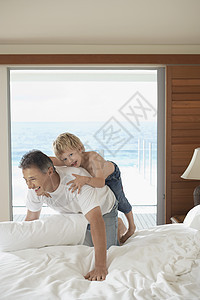 快乐的父亲和儿子一起在床上玩图片
