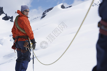 与雪山安全线相连的男性徒步旅行者图片