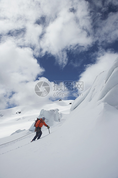 一只男性徒步者向雪山坡飞上云的侧面景色图片