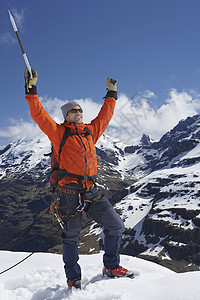 男性登山者举起手来 在雪峰顶上用冰夹假期登山远足背包地形享受冒险家远足者成人顶峰图片