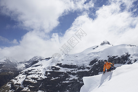 新西兰南岛男性登山者坐落在雪峰上 与山顶和云层交锋背景