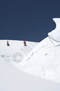 在雪山远处走过冰层的两座徒徒步者侧面景象图片