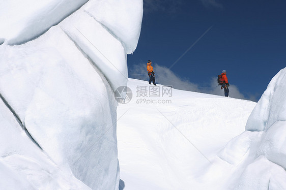 在雪山远处经过冰层的 两位徒步者的侧面景象活动男士假期勘探上坡远足者远足闲暇安全绳索图片