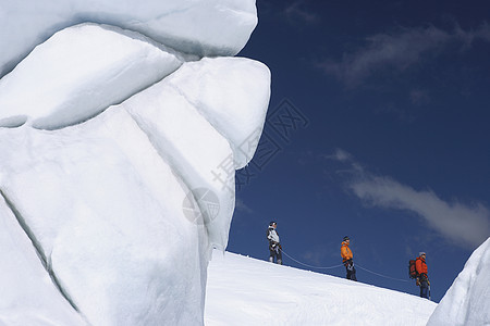 在雪山远处经过冰层形成 3个徒步登山者的侧面景色远足者旅行探索者滑雪勘探上坡活动远足娱乐闲暇图片