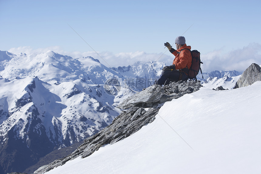 男性登山者拍摄山峰上雪山的照片图片