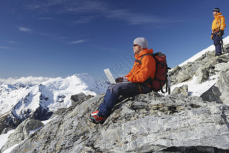新西兰南岛在山峰上使用笔记本电脑的 男性登山者的侧边视图高度顶峰运动冒险远足闲暇男士假期成人风景背景