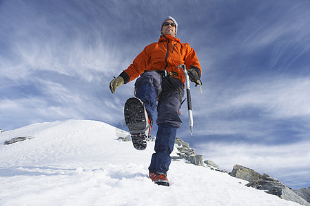 男性登山者在雪坡上徒步的低角度视图图片