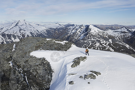 山上登山者的中距离拍摄 穿过雪 到达遥远的山峰图片