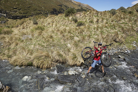 在河中骑自行车的赛车员运动员一人岩石中年场地成人太阳镜服装男人头盔图片