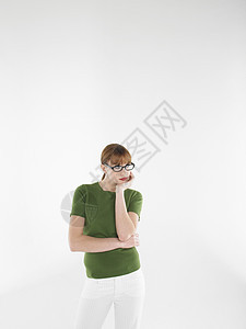身戴眼镜和绿色T恤的年轻无聊妇女站在白色背景下站立背景图片