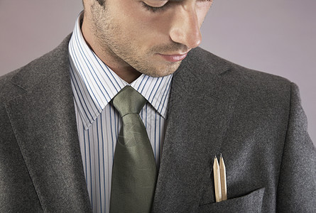一名年轻商务人士在紫色背景的口袋里用铅笔对一个年轻的商务人士进行检查男性裁剪商务公司套装夹克管理人员人士工人正装图片