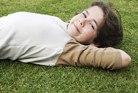 可爱小男孩的侧面肖像 头背靠在草地上图片
