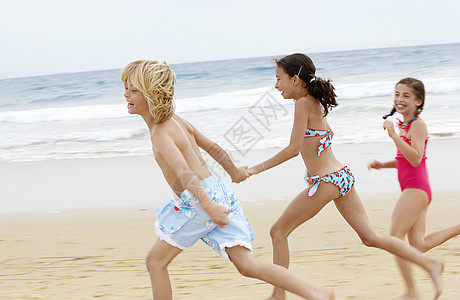 快乐的小朋友在沙滩上一起跑的侧面景色图片