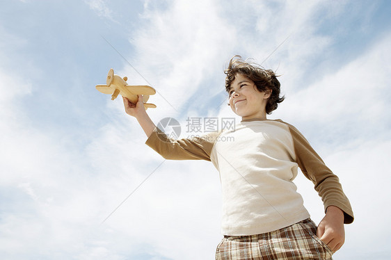 低角度观察可爱小男孩在云天上驾驶玩具飞机的低角度图片