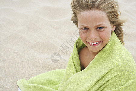 坐在沙滩上的毛巾裹着快乐的小男孩的肖像图片