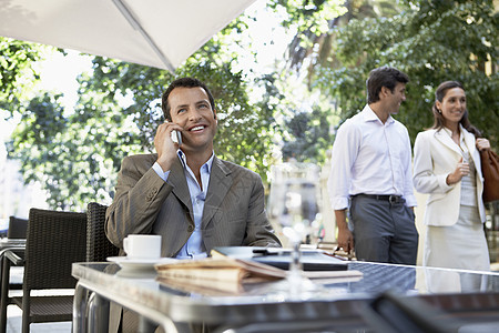 在户外咖啡馆使用移动电话的商务人士图片