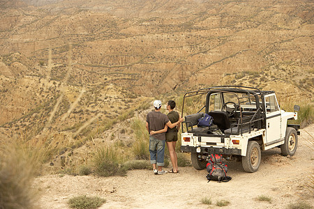 以四轮驱动车站在悬崖边的沙漠旁看着相亲情侣的近视闲暇旅行冒险男性女士文具越野男士女性运输图片