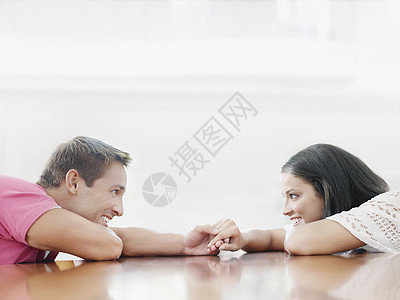 一对微笑的年轻夫妇 手牵手在桌子上看着对方的侧面图片