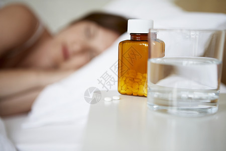 睡在床上的患病妇女 重点是前方的药瓶和水杯图片