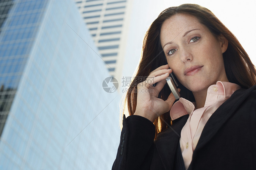 一名年轻女商务人士用手机对办公大楼进行纵向攻击的肖像图片