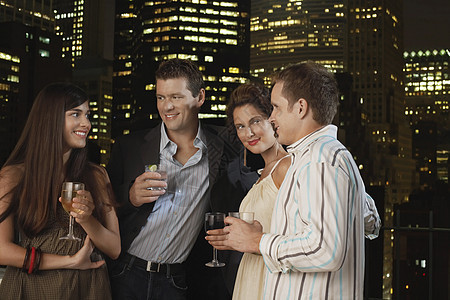两对年轻夫妇晚上在城市天际上 一起饮酒图片