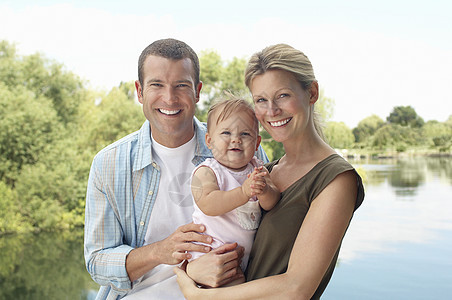 一对年轻夫妇的肖像 带着女婴站在湖边成人植物享受闲暇女士团结快乐幸福童年娱乐图片