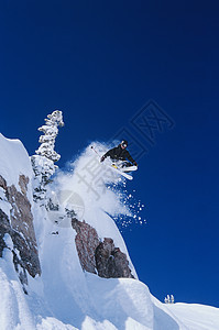 从山顶跳起的滑雪者成年人滑雪板悬崖蓝色活力娱乐天空冒险风险个性图片