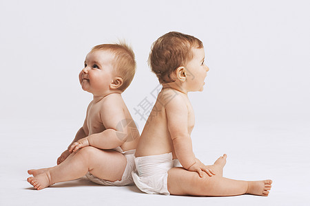 婴儿背靠背坐在白色背景上的侧边视图图片
