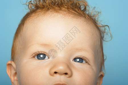 红发可爱婴儿的特写肖像 蓝背景被孤立图片