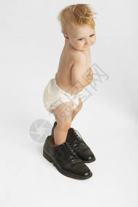 穿着男子鞋的长长可爱婴儿身穿男子鞋 在白色背景中被孤立图片
