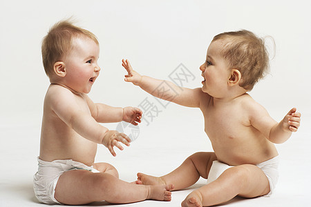 两个婴儿在白色背景下玩耍的侧边视图图片