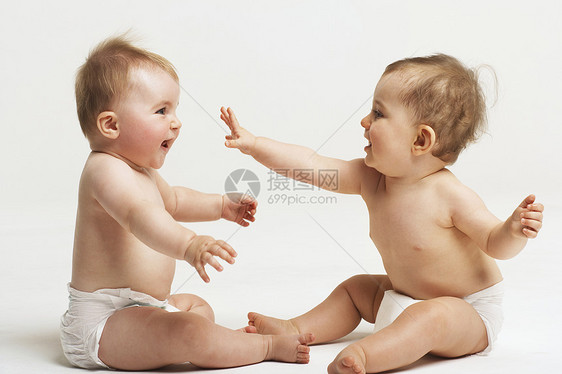 两个婴儿在白色背景下玩耍的侧边视图图片